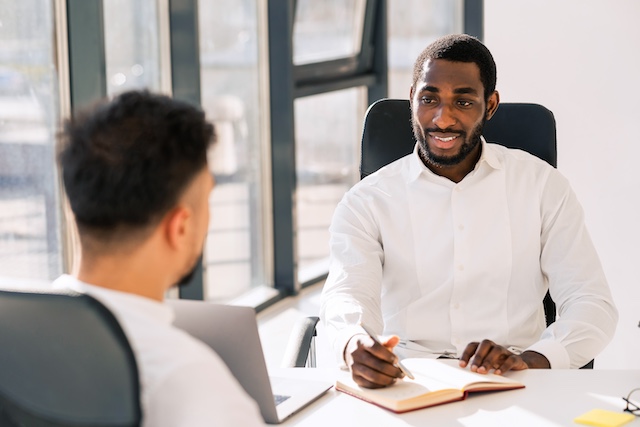 A Black male manager meets with an employee for his mid-year review