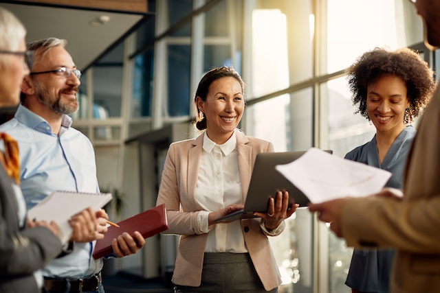 Asian female executive stands with colleagues following a meeting