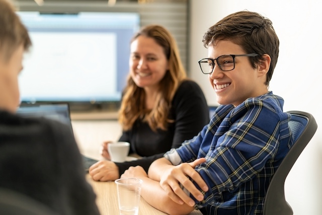 A young male intern smiles in a business meeting