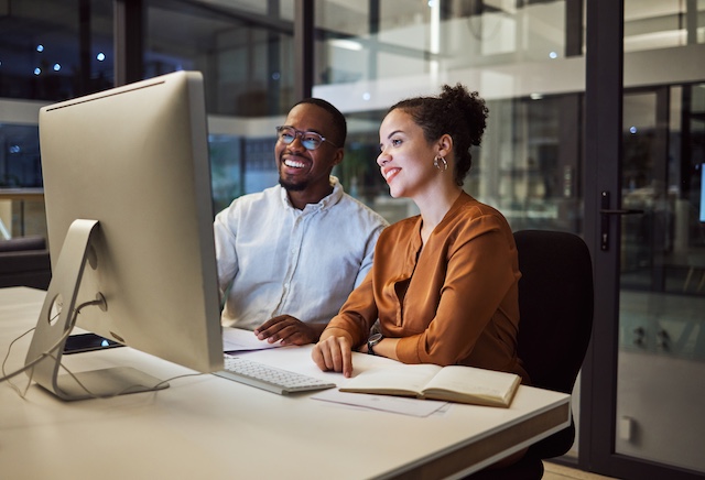 Two colleagues, one male and one female, collaborate effectively at work, having benefitted from employee coaching services