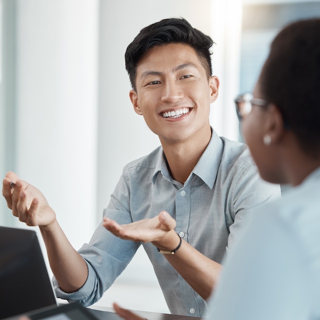 Smiling Asian male employee works with a female colleague.