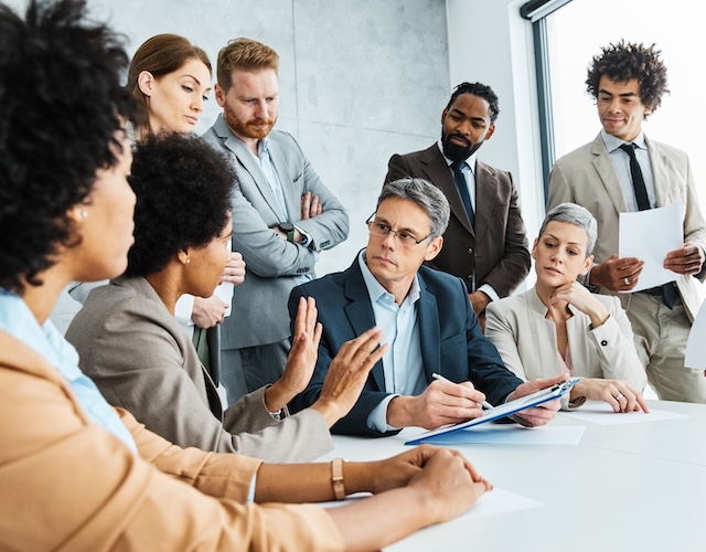 Diverse group of executives who have had executive coaching sit in a meeting