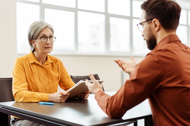 A female senior manager meets with her younger male employee to review his performance improvement plan