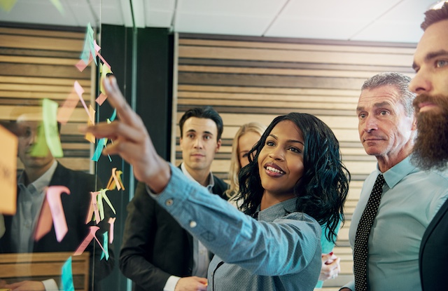 Young, smiling Black female leader heads a brainstorming session with her team