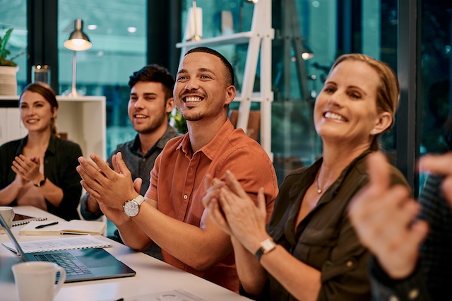 A work team applauds an achievement at a meeting