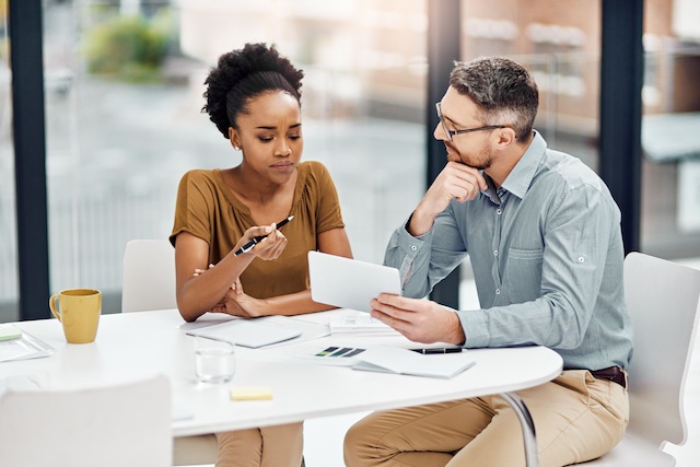 A male manager meets with a younger Black female employee to offer feedback