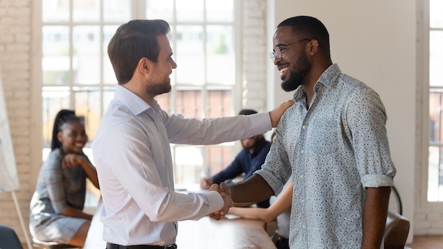 A male employee shakes the hand of a male colleague in appreciation