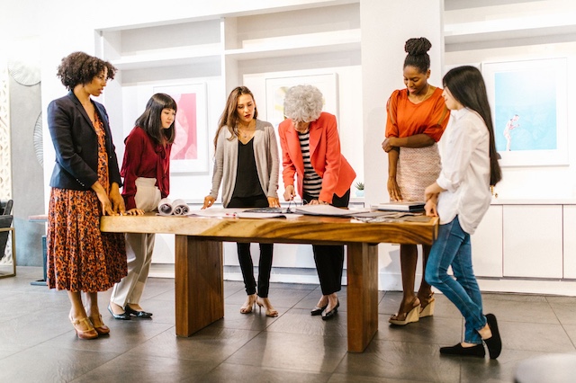 A group of female colleagues including executives, managers, and junior employees review a project